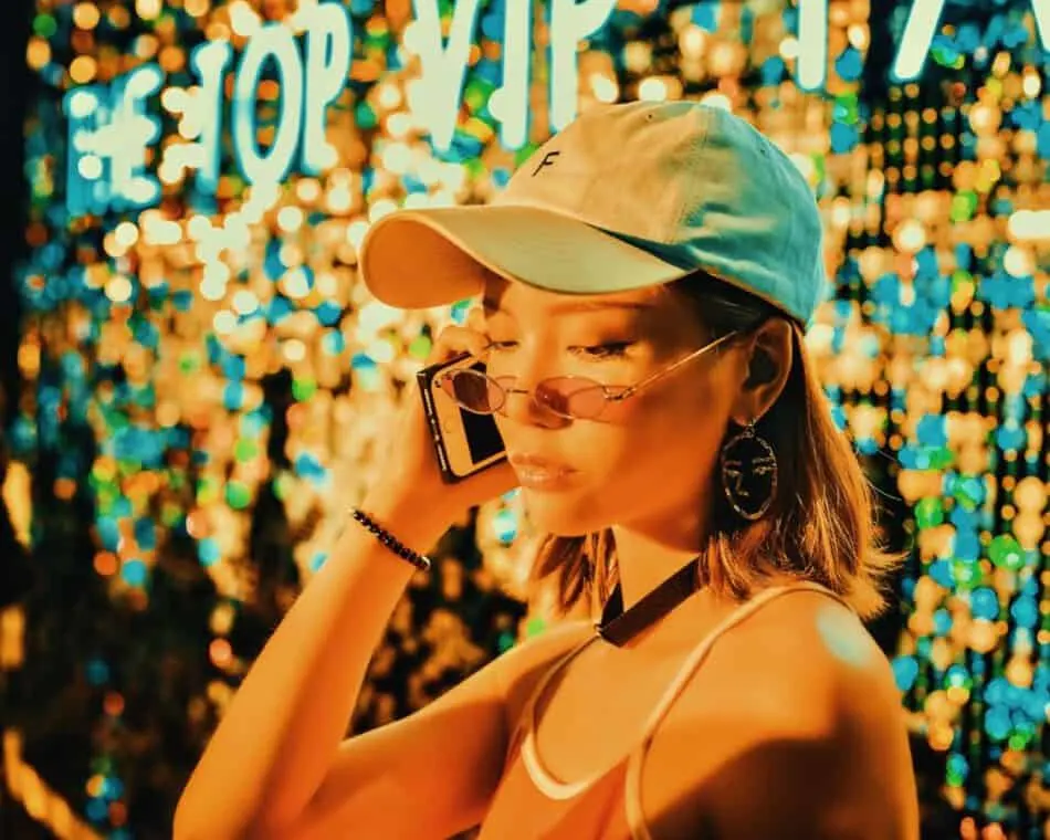 Woman making a phone call with an iPhone in front of colorful lights