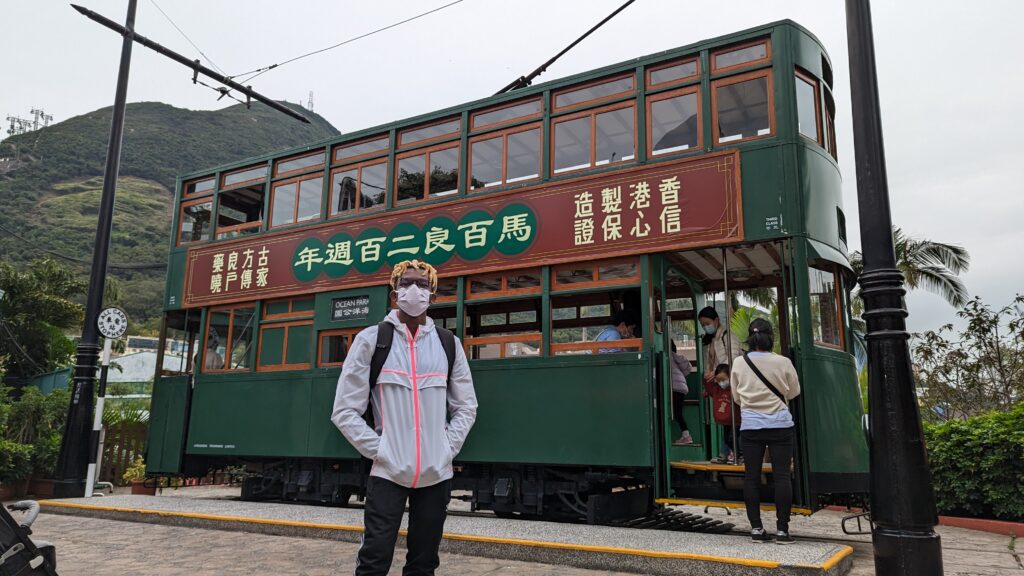Adu from Phone Travel Wiz in Front of an Old Tram in Hong Kong